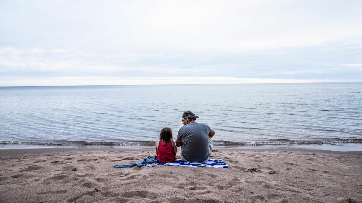 Rodzina na plaży zapatrzona w morze.