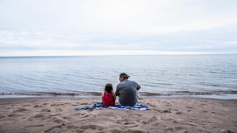 Rodzina na plaży zapatrzona w morze.