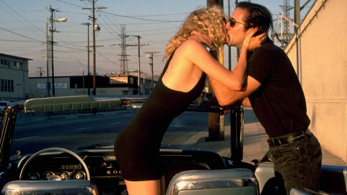 Kobieta wychylająca się z samochodu całuje mężczyznę.