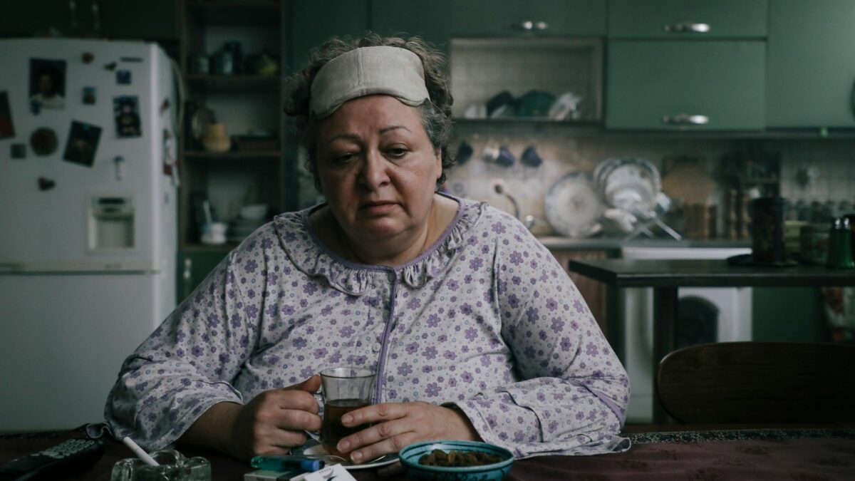 Kobieta w piżamie przy kuchennym stole.