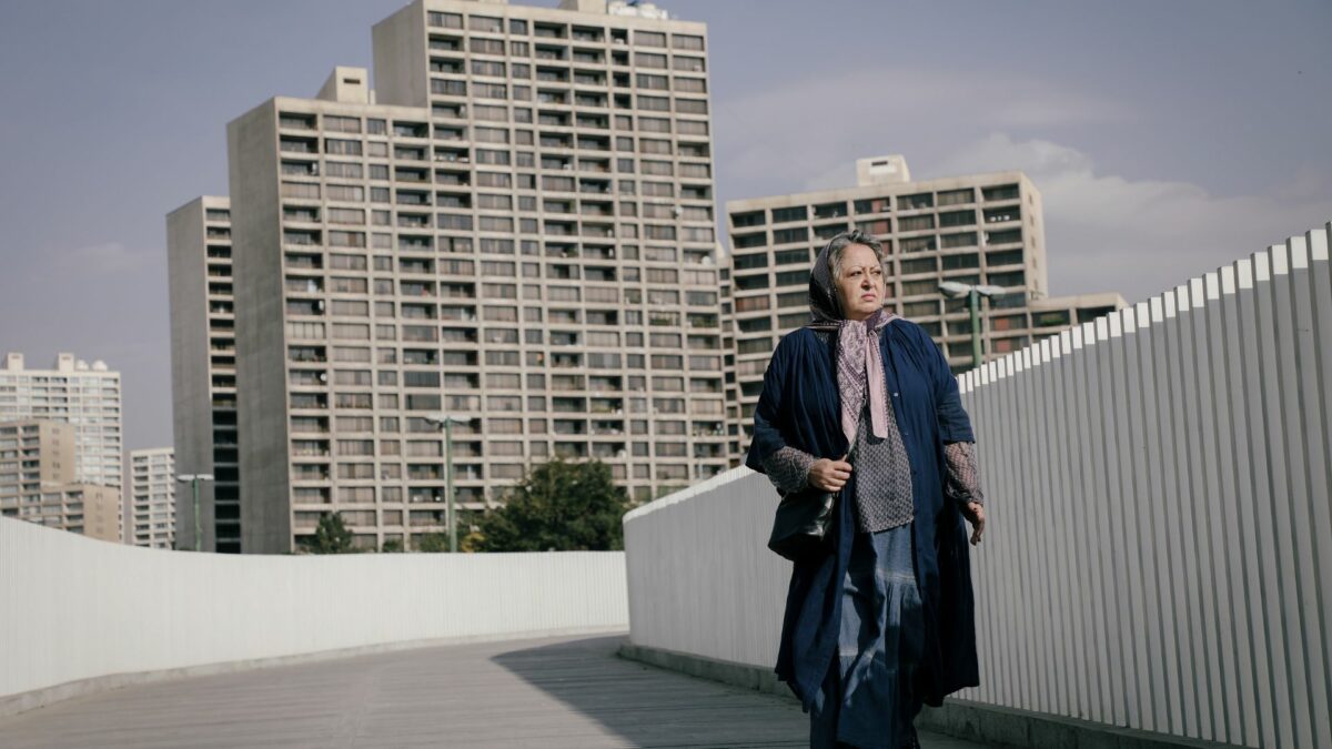 Kobieta spaceruje po ulicy na tle dużego blokowiska.