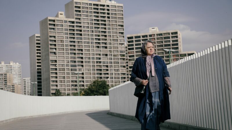 Kobieta spaceruje po ulicy na tle dużego blokowiska.