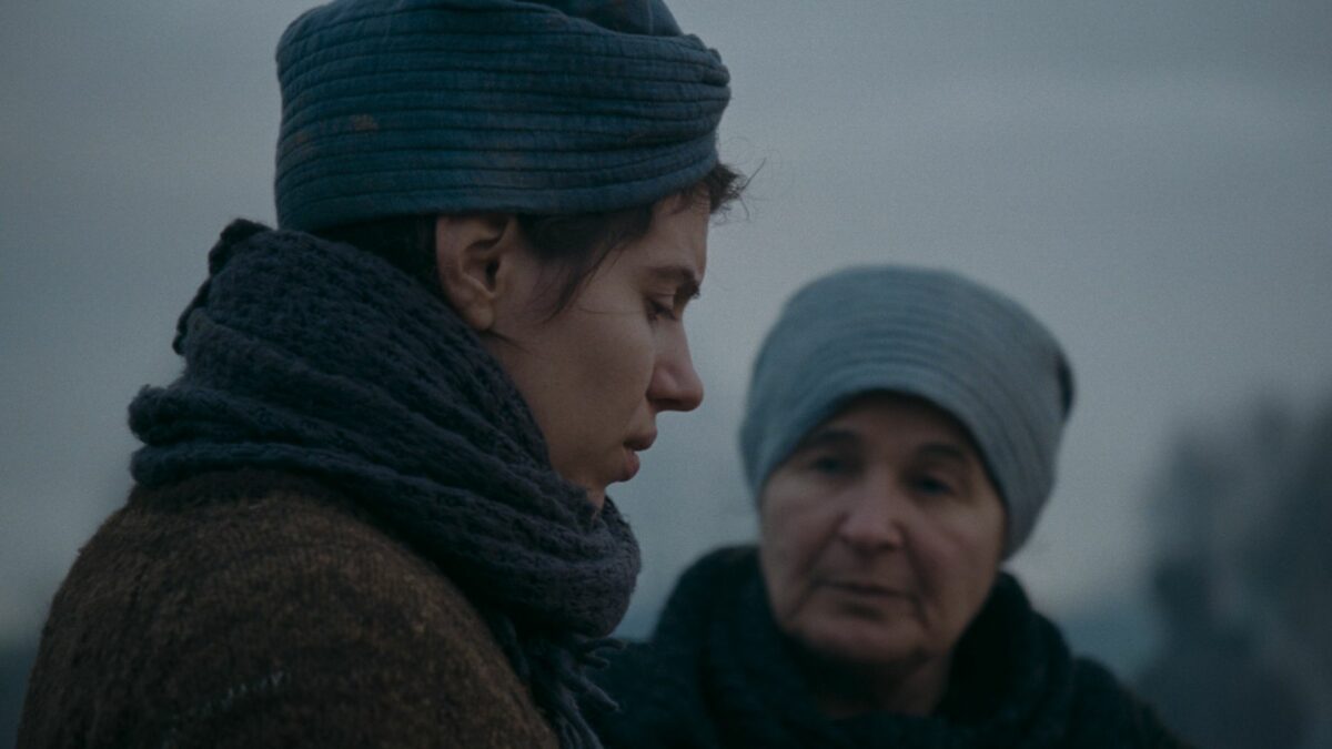 Starsza kobieta rozmawia z młodą dziewczyną na polu.