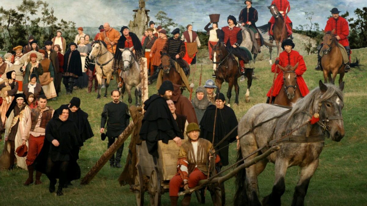 Kadr z filmu inspirowany obrazem Droga Krzyżowa. Pochód ludzi na koniach i wozach.