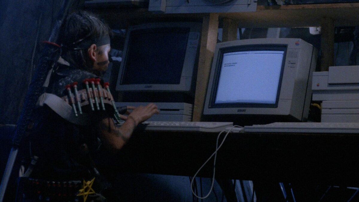 Chłopiec przebrany za Rambo siedzi przy komputerze.