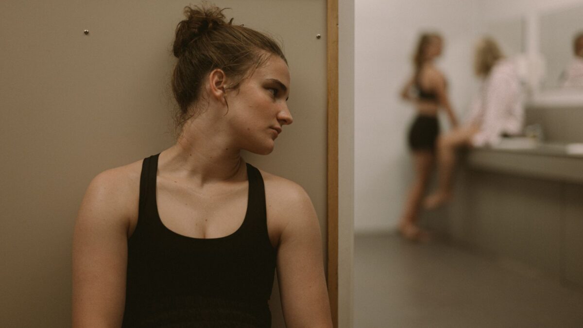 Dziewczyna podsłuchująca w szatni inne dziewczyny.