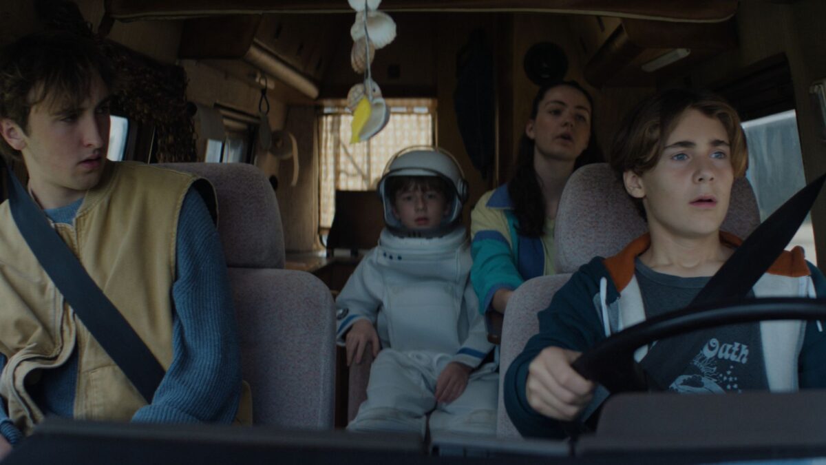 Jazda samochodem, na tylnym siedzeniu jest chłopiec przebrany za astronautę.