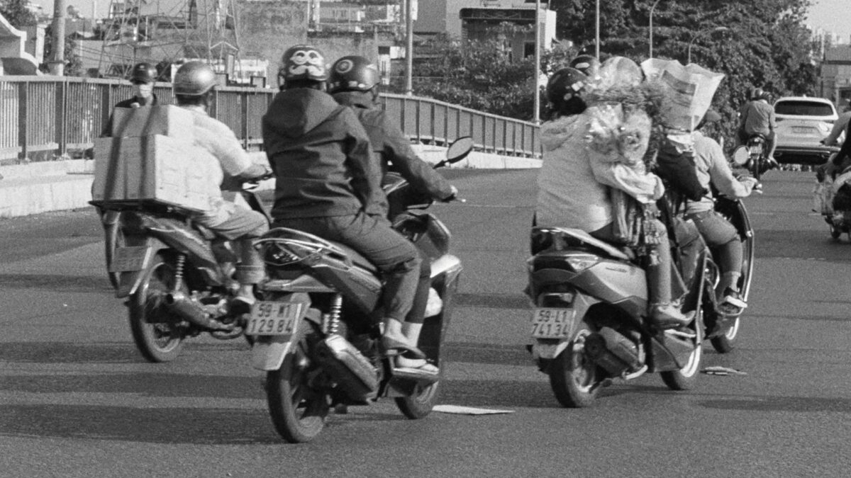 Kadr z ulicy pokazuję grupę ludzi jedzącą na skuterach.