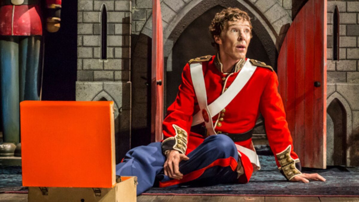 Kadr ze sceny teatralnej a na niej siedzi aktor, za nim scenografia zamku.