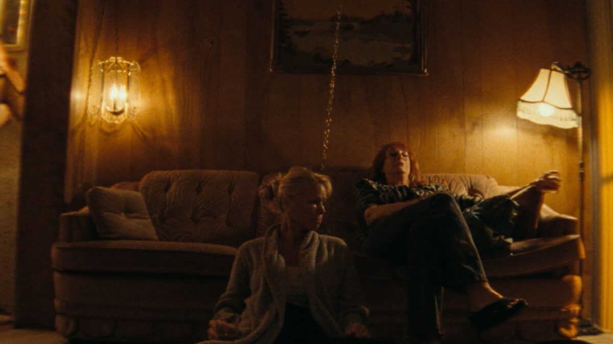 Dwie kobiety na kanapie w ciemnym salonie.