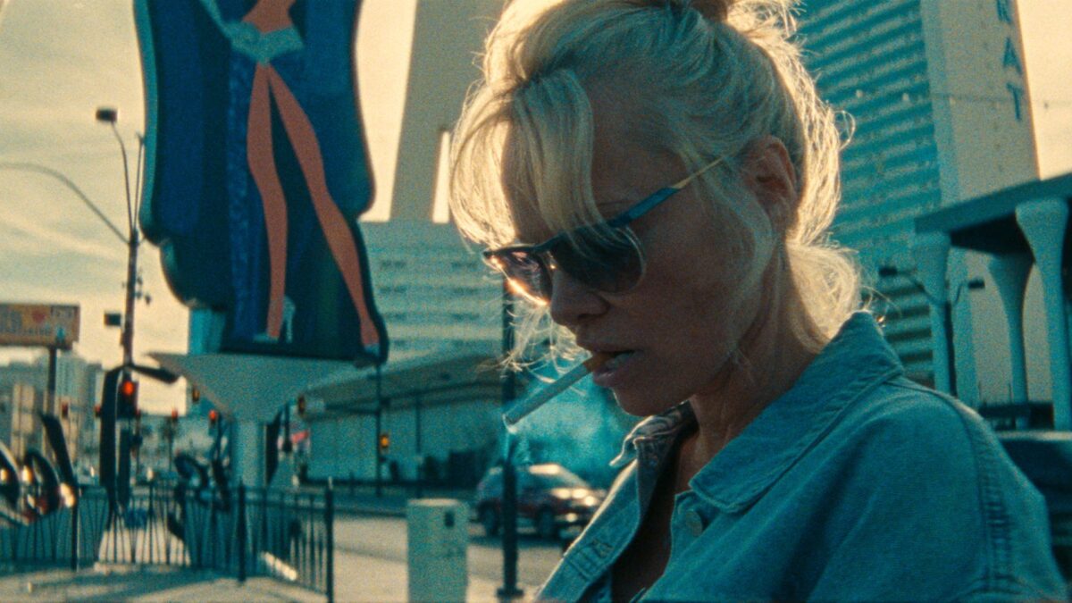 Kobieta odpalająca papierosa na ulicy.