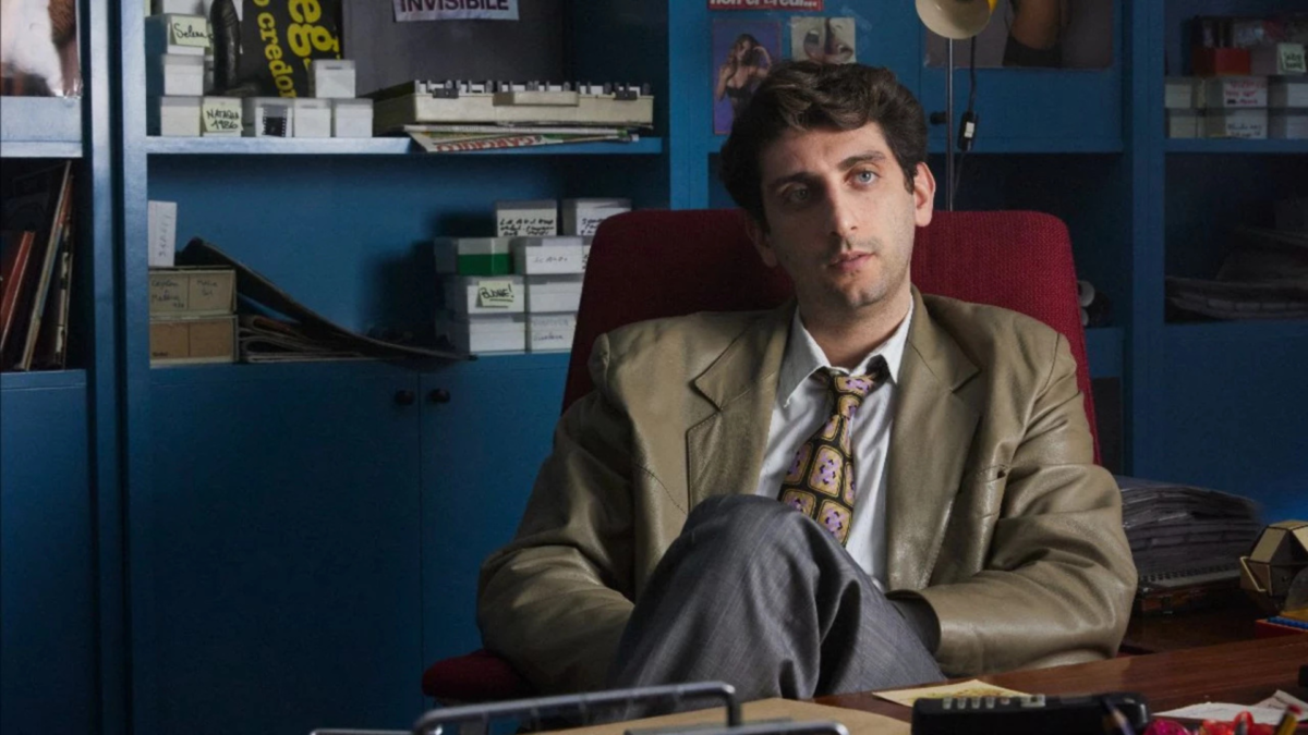 Mężczyzna w pracy siedzi za biurkiem.