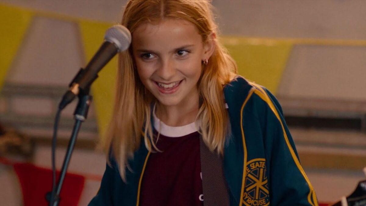 Młoda wokalistka z gitarą przed mikrofonem.