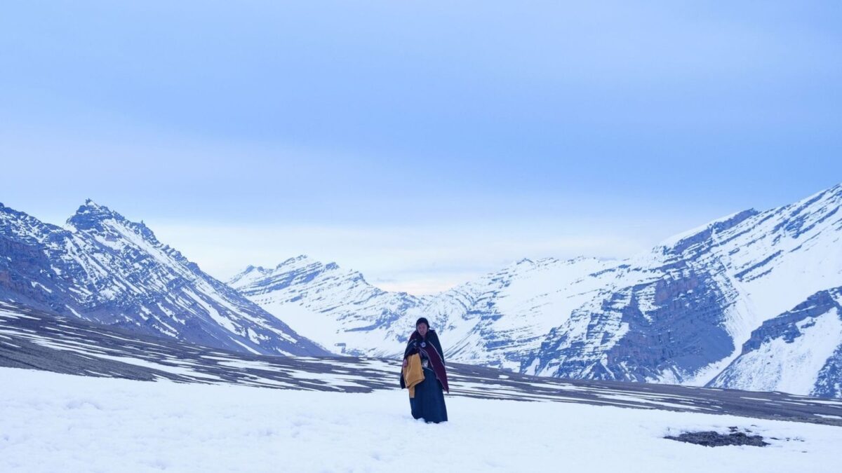 Kobieta na tle ośnieżonego, górskiego krajobrazu.