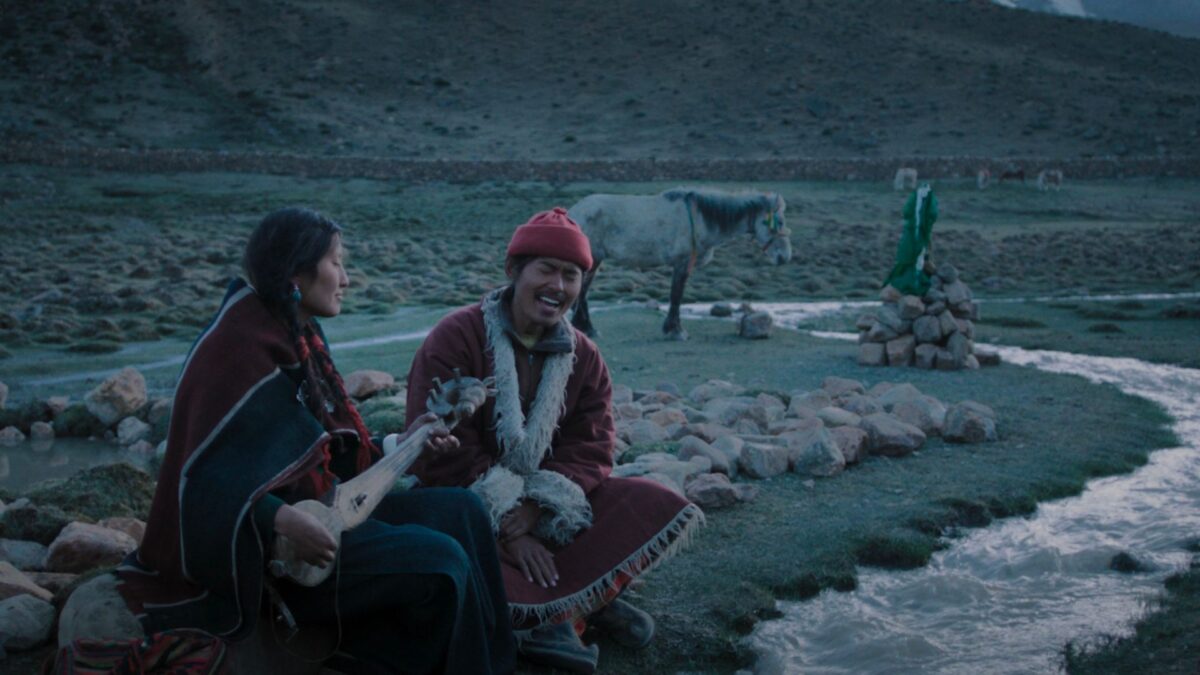 Kadr z pustkowia, para siedzi przy ognisku późną porą.