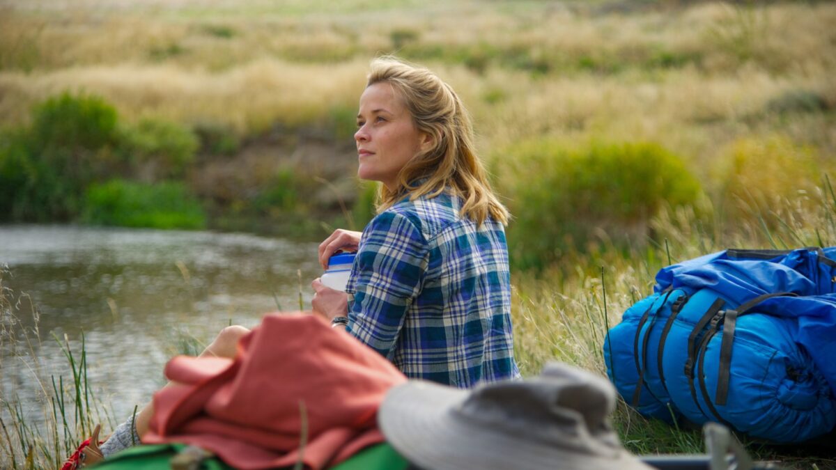 Kobieta odpoczywająca z bagażem na górskiej polanie.