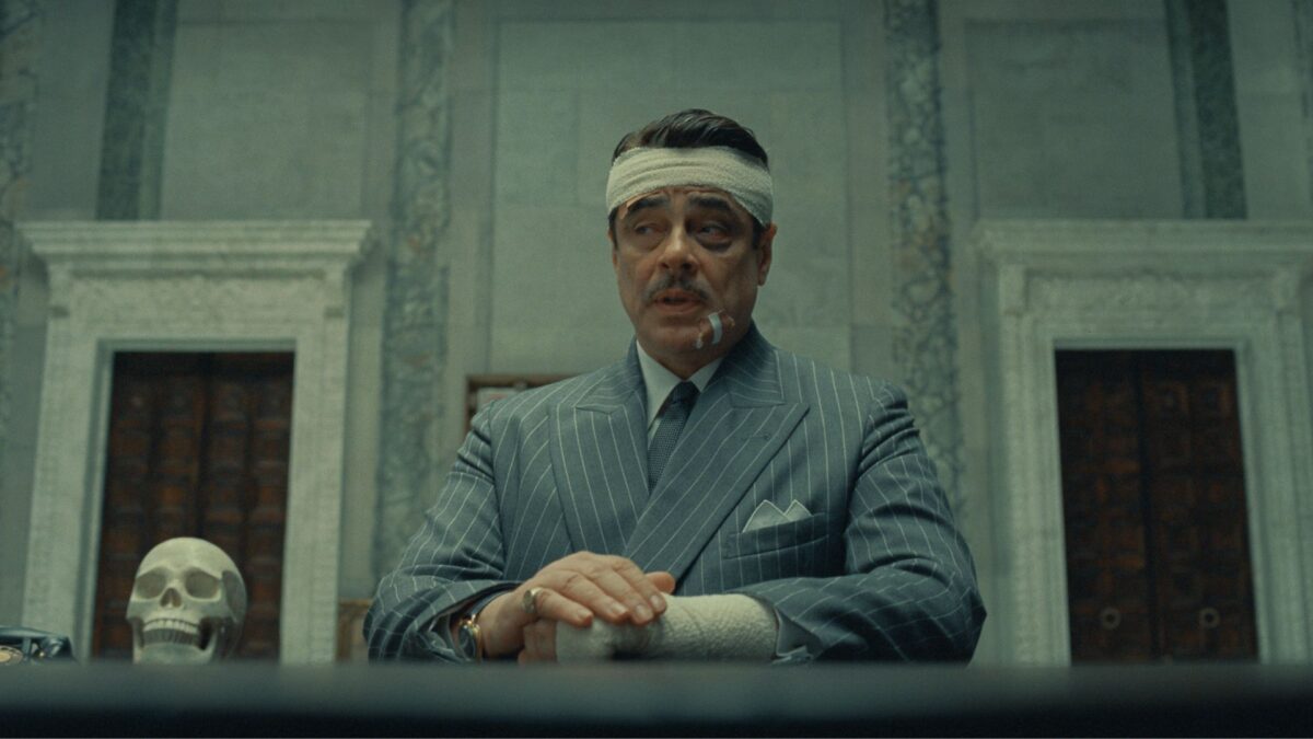 Mężczyzna z opatrunkami na twarzy siedzi za biurkiem.