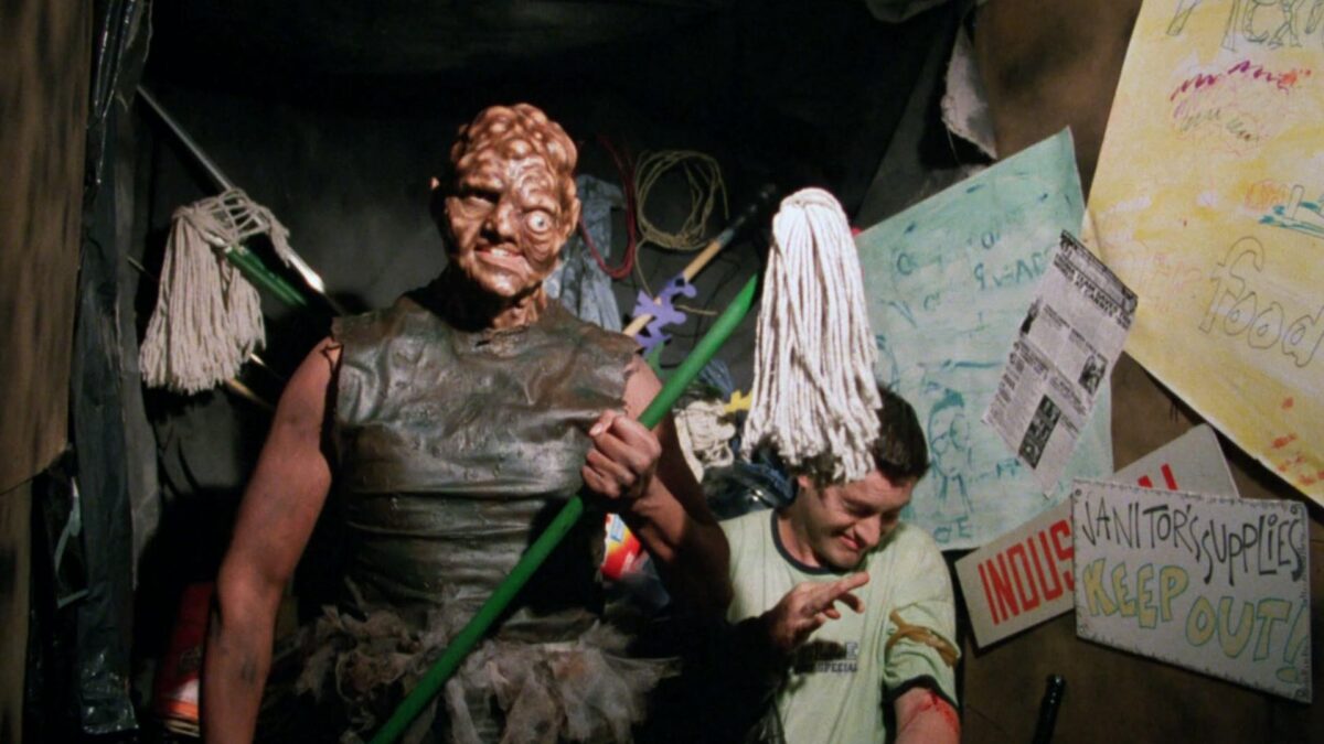 Zmutowany człowiek z mopem w dłoniach.