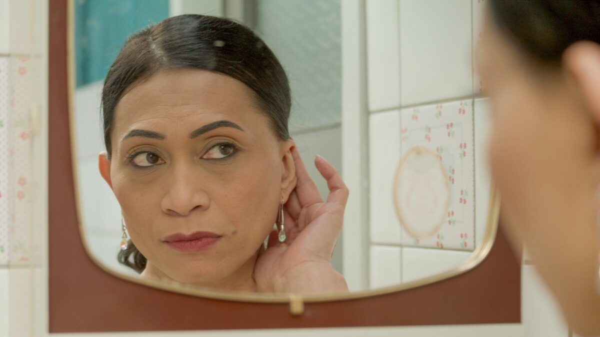 Kobieta zakładająca kolczyki przed lustrem.