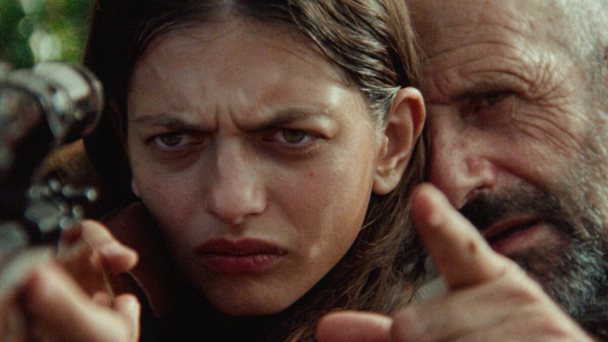 Mężczyzna uczy strzelania z broni młodą dziewczynę.