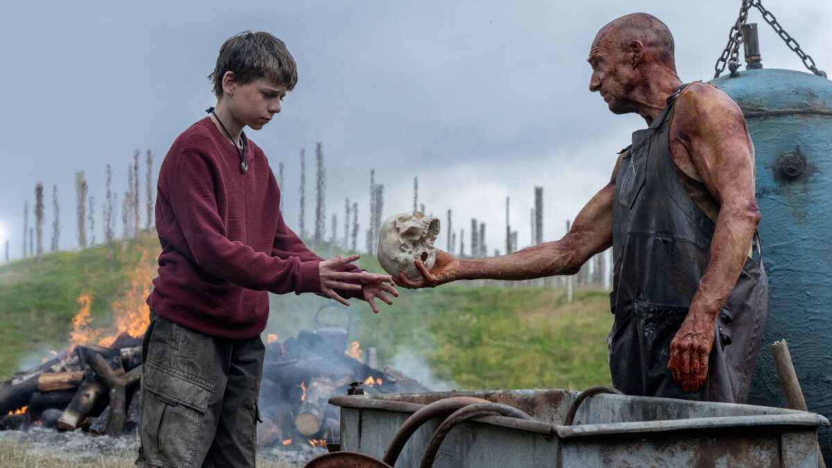 Mężczyzna podaję czaszkę młodemu chłopakowi.